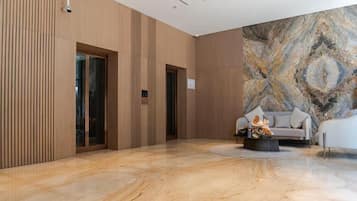 Un'ampia hall con pavimento in marmo, un divano e una parete decorativa.