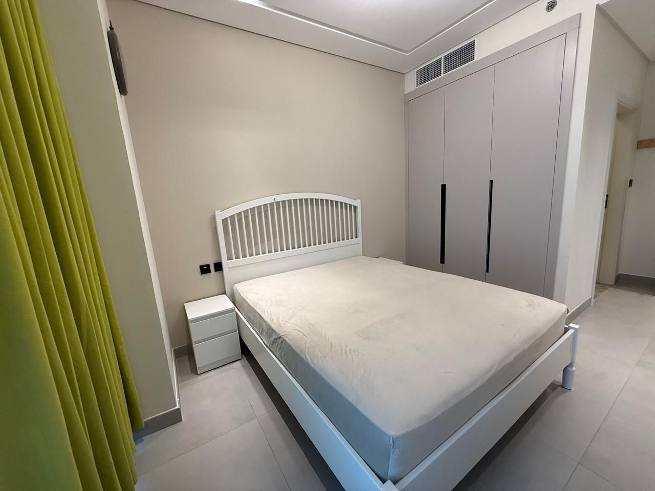 Una camera da letto con un letto, un comodino, un armadio e una tenda.