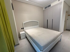 Una camera da letto con un letto, un comodino, un armadio e una tenda.