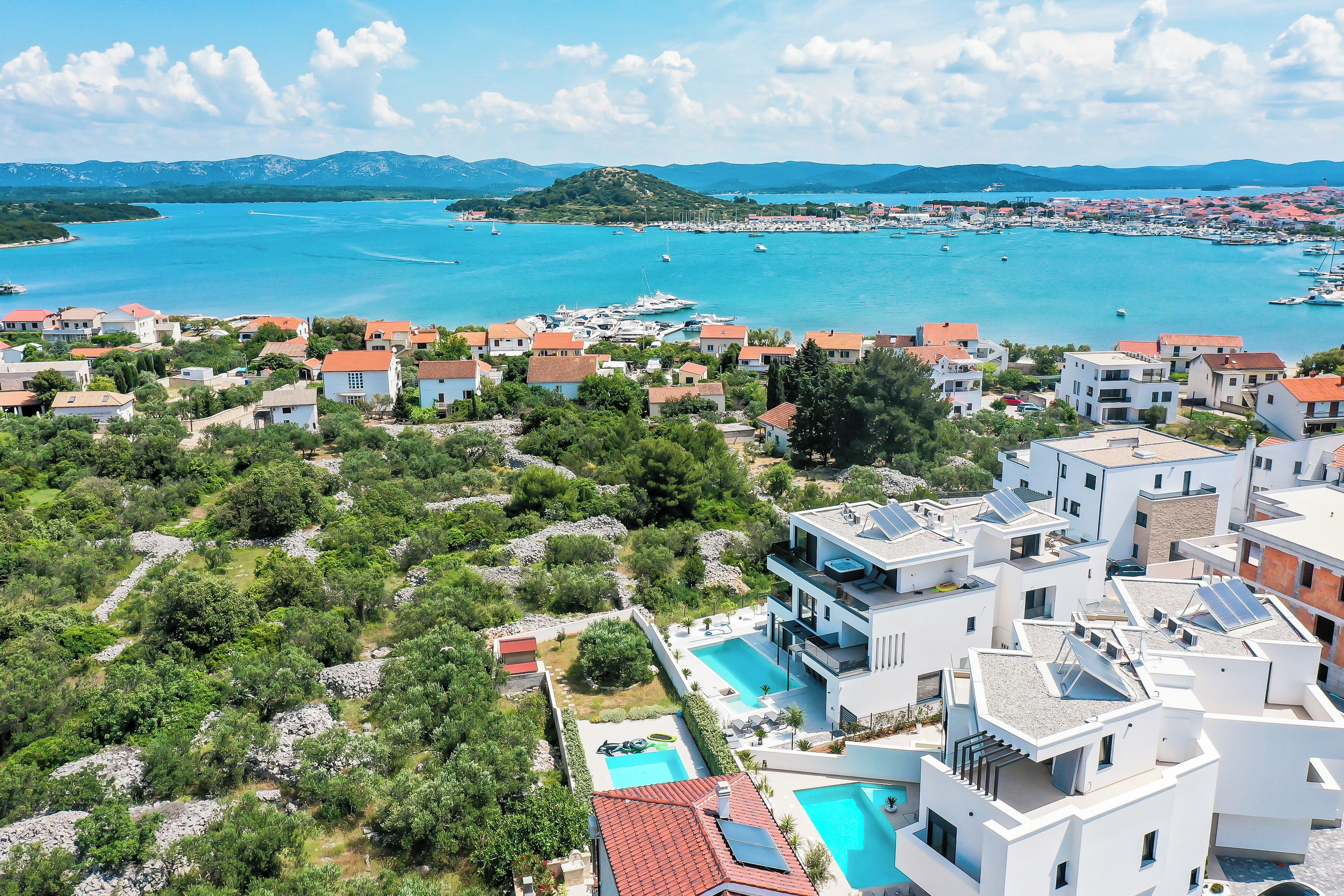 A coastal residential area with modern buildings, a marina, and a clear view of the sea.