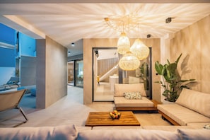 Una sala moderna con sofá, mesa de centro y lámparas colgantes.