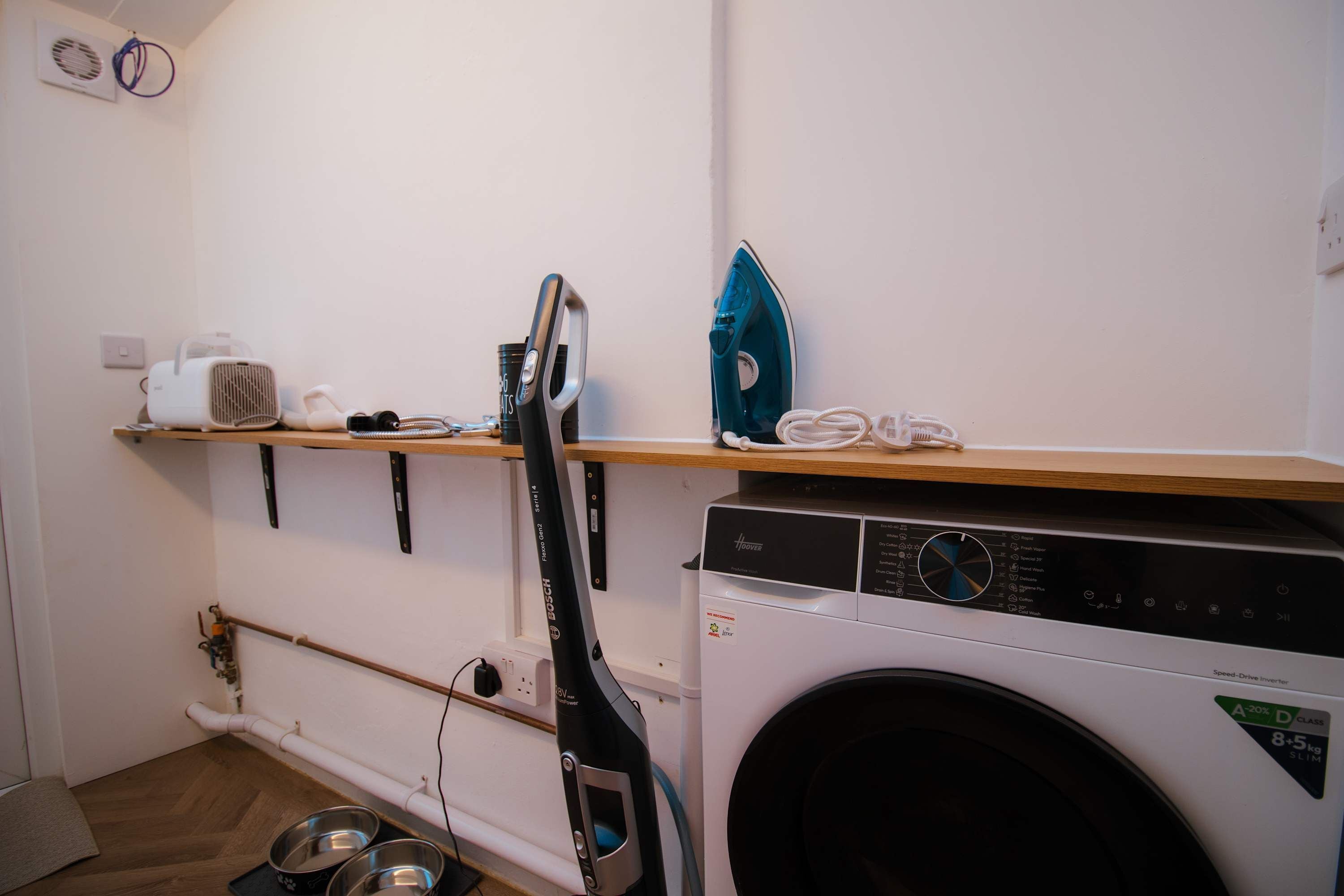 A laundry room with a Bosch washing machine, a hanging rack, and a wall-mounted heater.