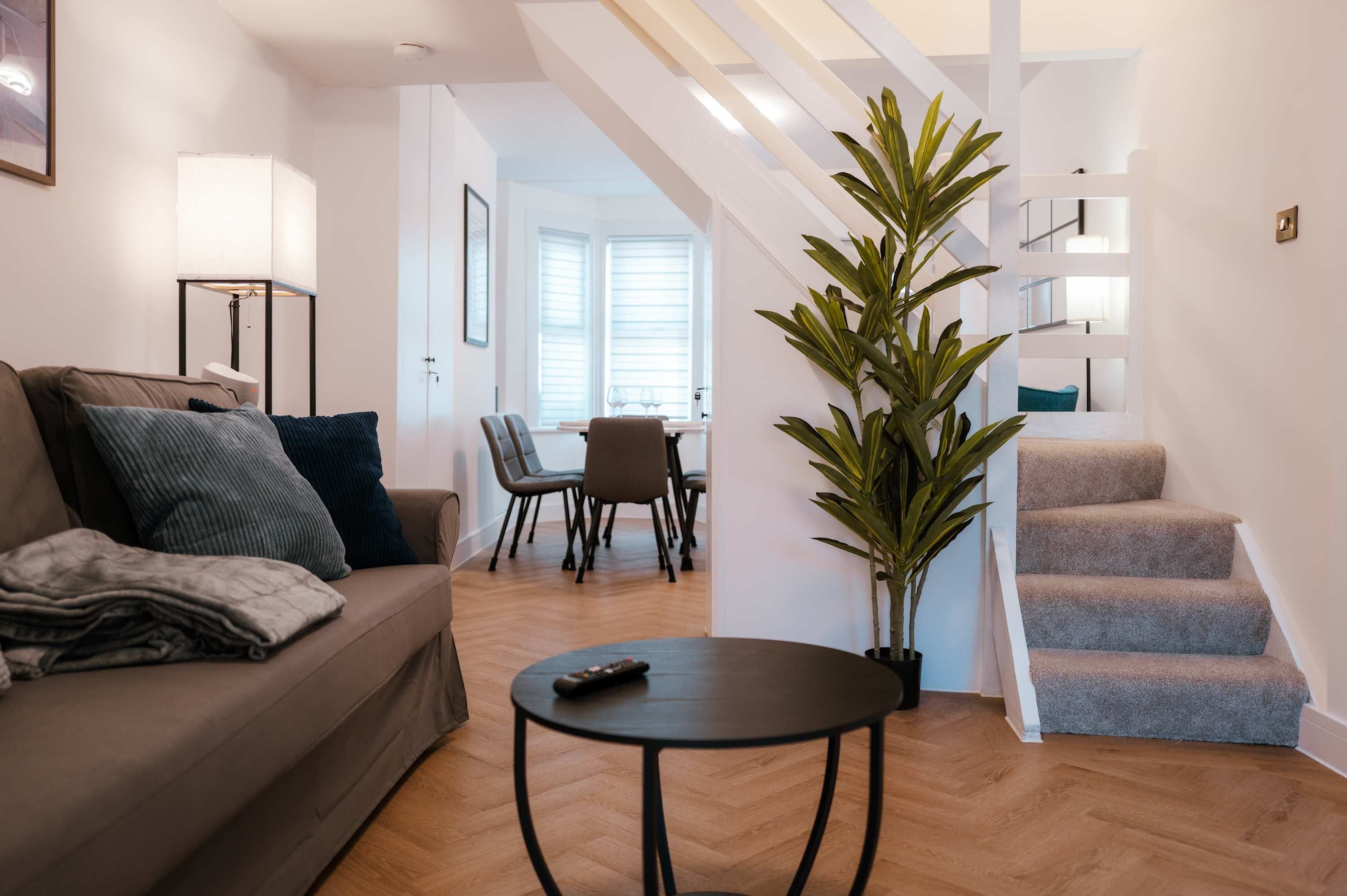 A modern living room with a sofa, a coffee table, and a staircase.