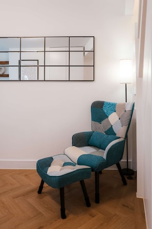 A teal armchair with a patchwork cushion and a matching ottoman in a room with a wooden floor and a white wall. - Perfect Booking 2-bed Near Folkestone Harbour (Folkestone)