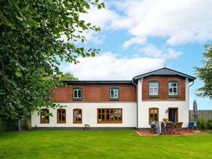 A two-story house with a brick exterior and white walls, a front yard, and a patio with outdoor furniture. - Hoheluft Country House (Steinberg)