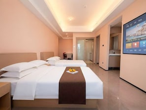 Een hotelkamer met twee bedden, een klein tafeltje met fruit, een televisie en een badkamer zichtbaar door een geopende deur.