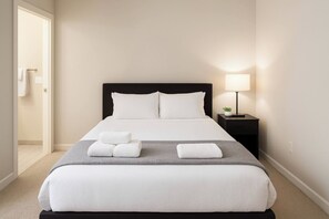 Ein Hotelzimmer mit einem Bett, einem Nachttisch mit Lampe und einer Tür zu einem Badezimmer.