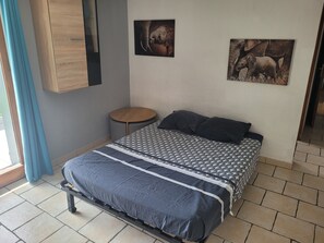Une chambre à coucher avec un lit, une petite table ronde et deux tableaux accrochés au mur.