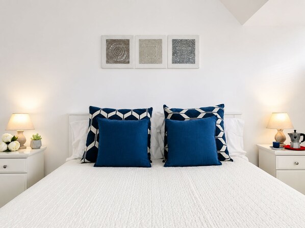 A bed with two pillows, a bedside table with a lamp, and a wall with three framed artworks. - New Listing (Napoli)