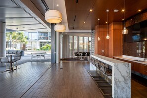 Eine moderne Hotelhalle mit Barbereich, Sitzgelegenheiten und Blick ins Freie.