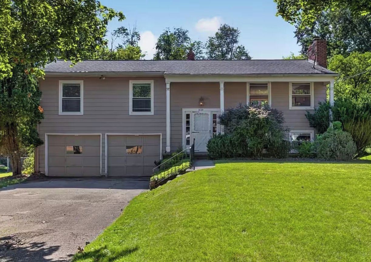 A two-story house with a garage, a front door, and a small porch.