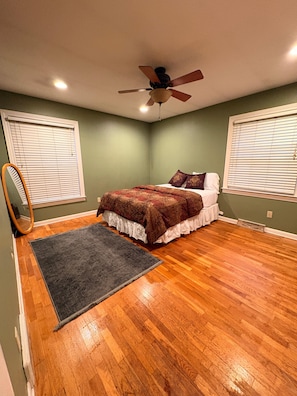 Un dormitorio con una cama, un ventilador de techo y suelo de madera.