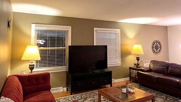 A living room with a television, two lamps, a sofa, and a coffee table.