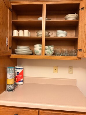Un mueble de cocina con estantes que contienen platos, tazones y vasos.
