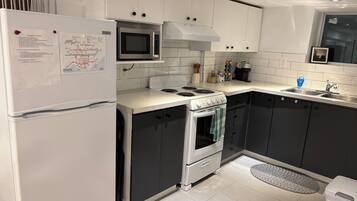 A modern kitchen with white cabinets, a stainless steel microwave, a gas stove, and a built-in oven.