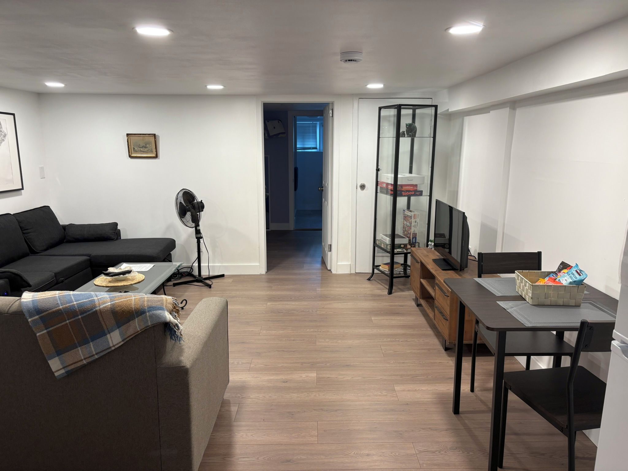 A modern living room with a sofa, a coffee table, a TV, and a dining area with a table and chairs.