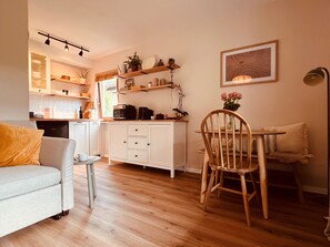 A modern kitchen with white cabinets, a dining table with chairs, and a sofa in a living area. - Small, cozy, charming—a bright home in Chiemgau (Ruhpolding)