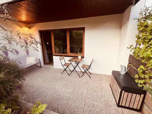 A covered patio with a table and chairs, a bench, and a potted plant. - Small, cozy, charming—a bright home in Chiemgau (Ruhpolding)