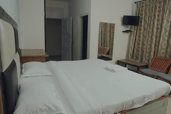 A hotel room with a bed, a television, a chair, and a small table.