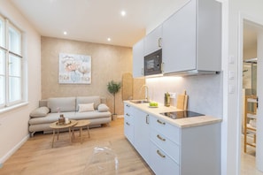 A modern kitchen with a built-in microwave, a sink, and a countertop. There is a sofa and a small table with a vase and a candle. - Luxury Boutique Apartment | Heart of Old Town (Prague 1)