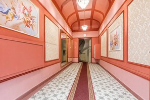 A hallway with a patterned floor, a red carpet, and framed artwork on the walls. - Luxury Boutique Apartment | Heart of Old Town (Prague 1)