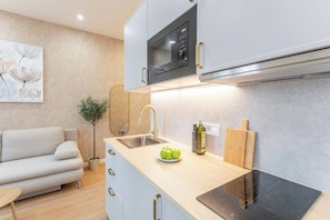 A modern kitchen with a built-in microwave, a sink, and a countertop with a plate of apples. - Luxury Boutique Apartment | Heart of Old Town (Prague 1)