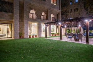 Ein Innenhof mit einer Pergola, Sitzgelegenheiten im Freien und einem Poolbereich.