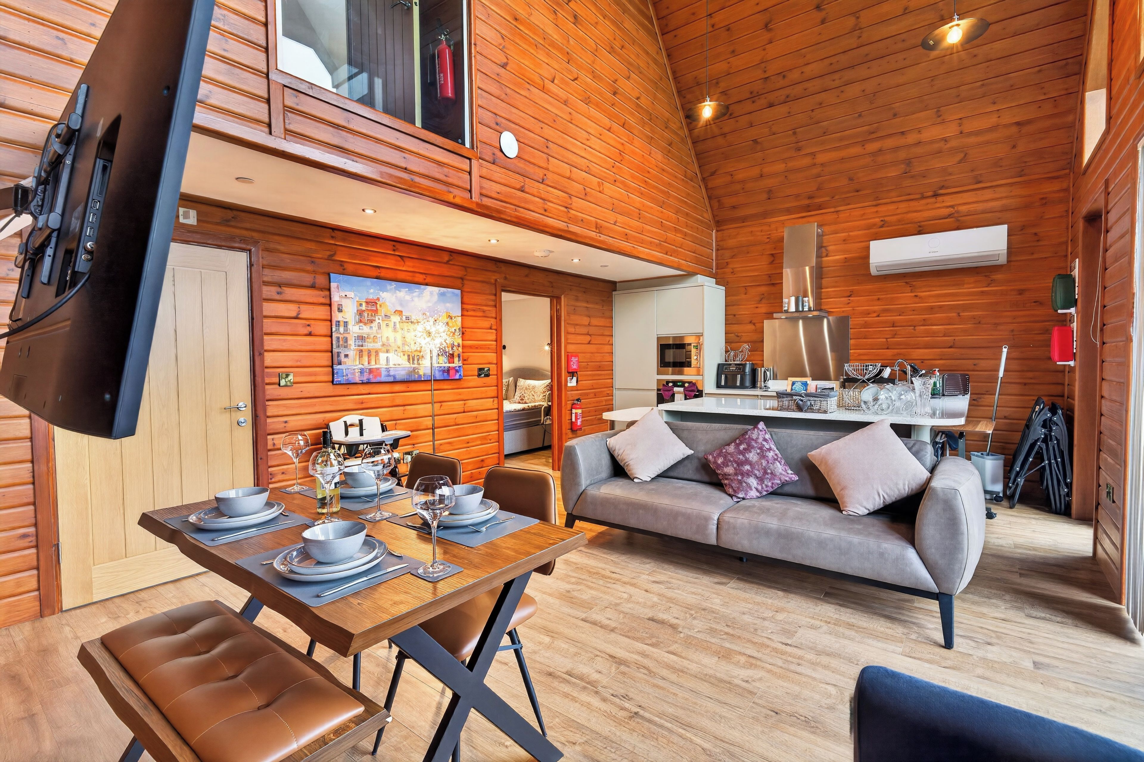 A cozy cabin interior with a dining area, sofa, and kitchenette.