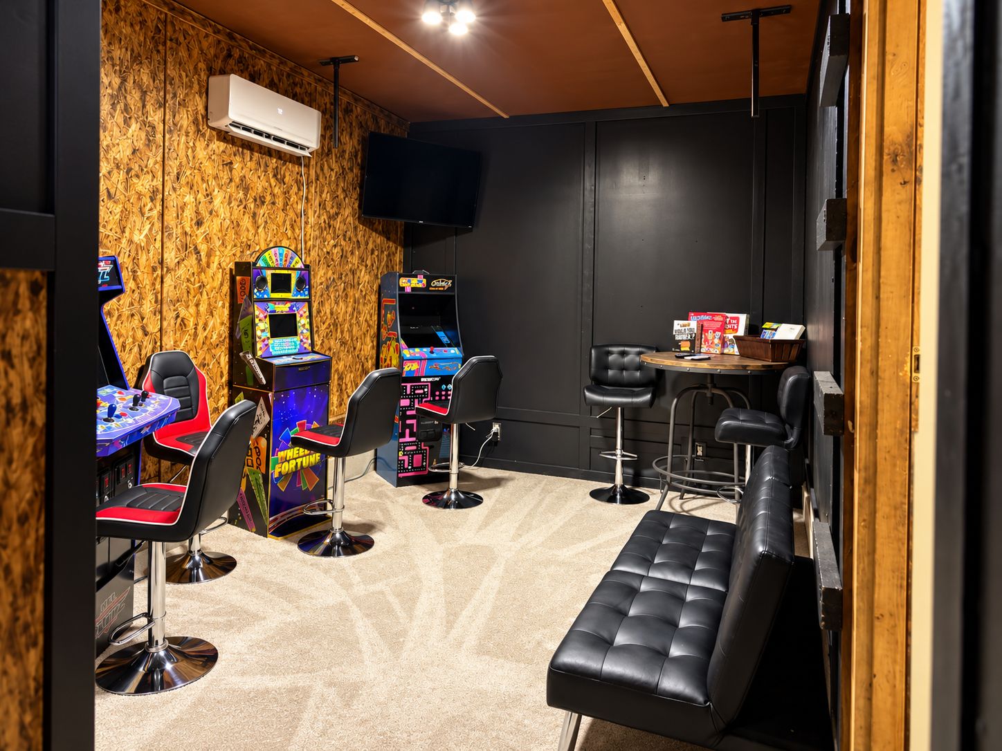 Un espace bar équipé de jeux d’arcade, de tabourets et d’un banc.