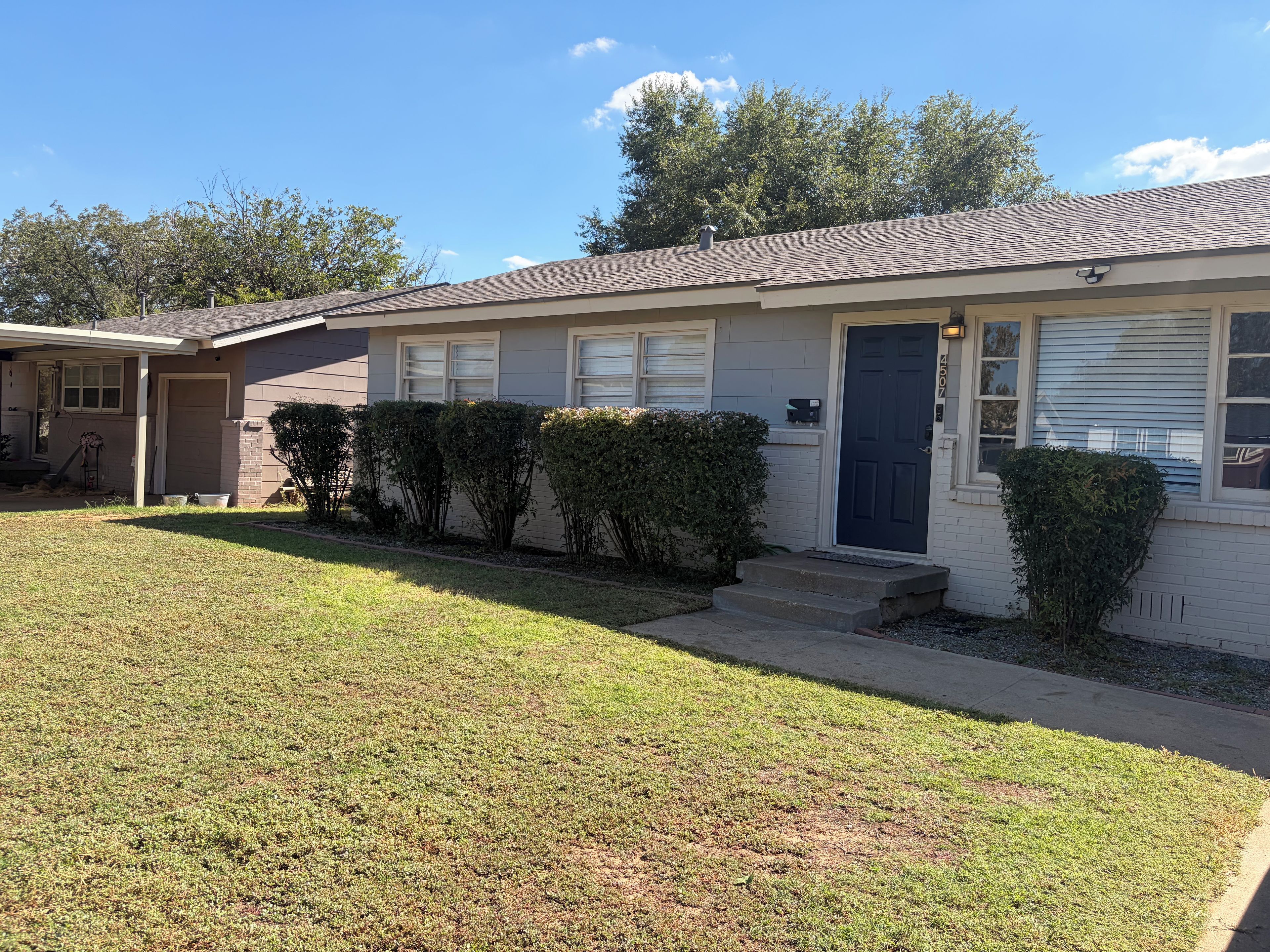 A single-story house with a front door, a garage, and a small front yard.
