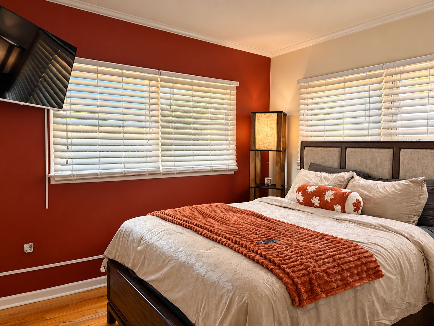 A bedroom with a bed, a nightstand, a lamp, and a wall-mounted TV.