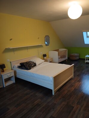 Une chambre à coucher avec un lit, une table de chevet, une commode et un berceau.