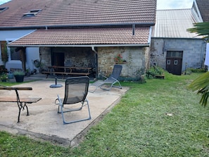 Un patio con mesa, sillas y un muro de piedra.