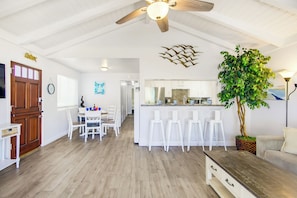 A spacious kitchen with white cabinets, a central island with stools, and a ceiling fan. - Short Walk To Sand Prefect For Families, Lrg Patio (Newport Beach)