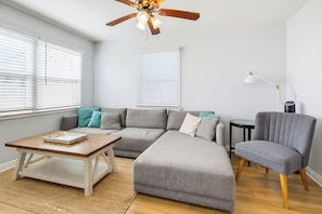 A modern living room with a sectional sofa, a coffee table, a side table, a floor lamp, and a ceiling fan. - Perfect For Families, Walk To Beach & Shops! (Newport Beach)