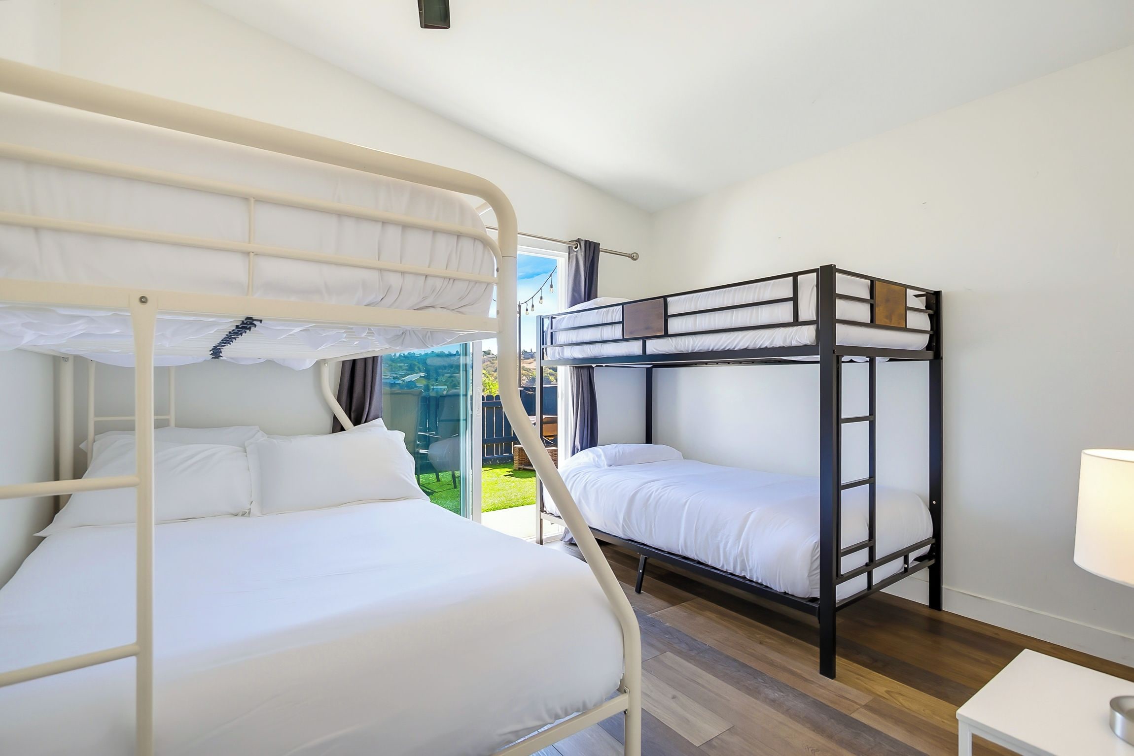 Une chambre avec un lit superposé, une fenêtre, une petite table et une lampe.
