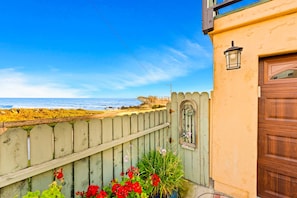 Um imóvel costeiro com cerca de madeira, porta com janela e vista para o mar.