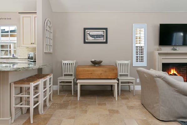 A living room with a fireplace, a television, and a dining area with a wooden table and chairs. - Perfect For Families, Walk To Beach & Park! (Ventura)