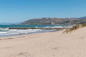 A beach with a rocky breakwater, a clear sky, and distant mountains. - Perfect For Families, Walk To Beach & Park! (Ventura)