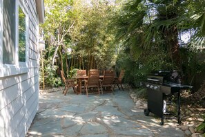 A patio with stone flooring, a wooden table with chairs, and a barbecue grill. - Perfect For Families, Walk To Beach & Park! (Ventura)