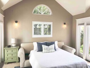 A bedroom with a bed, a nightstand, a window with blinds, and a wall-mounted light fixture. - Perfect For Families, Walk To Beach & Park! (Ventura)