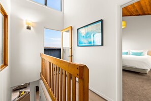 A staircase with a wooden handrail leading to a bedroom with a bed and a framed map on the wall. - Oceanfront Retreat, Amazing Ocean Views W/Jacuzzi! (Ventura)