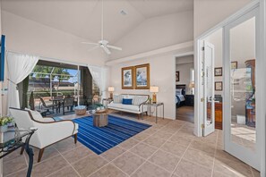 A spacious living area with a ceiling fan, a dining table with chairs, a sofa, and a blue patterned rug. - Cape Escape your waterfront getaway in SW Cape Coral (Cape Coral)