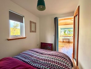 A bedroom with a bed, a window, and a door leading to an outdoor area. - Seaview One Bed Annexe - Pets Welcome - Parking (Isle of Lewis)