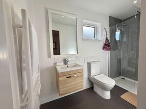 A modern bathroom with a toilet, sink, mirror, and shower. - Seaview One Bed Annexe - Pets Welcome - Parking (Isle of Lewis)