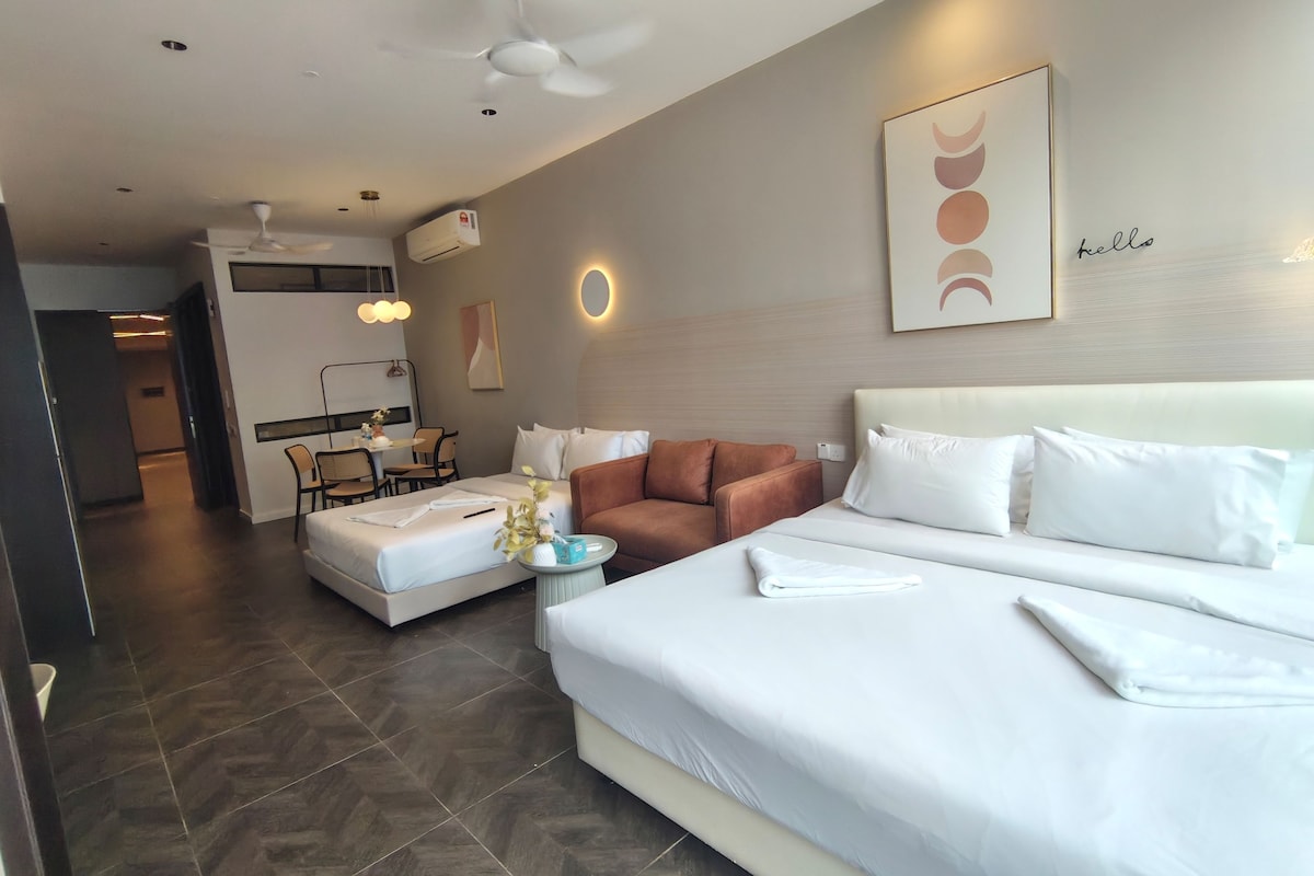 A hotel room with a large bed, a sofa, a dining area, and a ceiling fan.