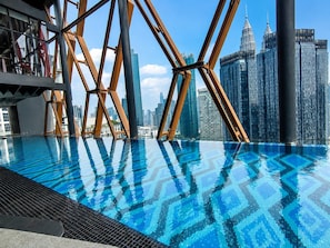 A rooftop infinity pool with a patterned floor, surrounded by a modern metal structure, overlooking a city skyline with high-rise buildings. - Scarletz KLCC By Solvane Hospitality  (Kuala Lumpur)
