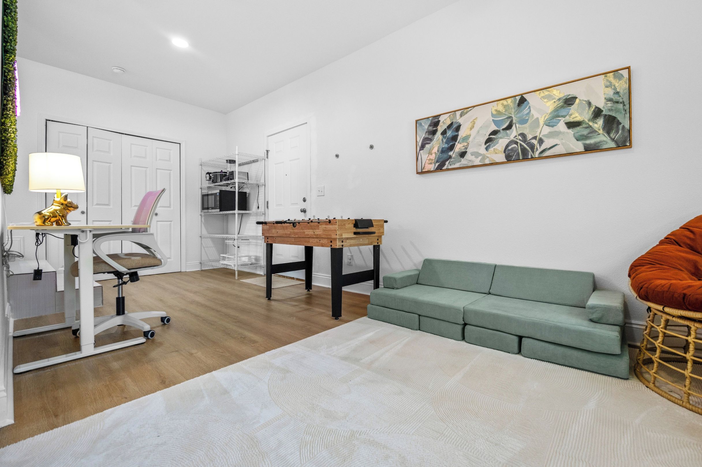 A modern living room with a sofa, a table, a lamp, and a wall-mounted artwork.