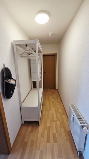 Ein schmaler Flur mit einem Etagenbett, einem Heizkörper und einer Tür am Ende.