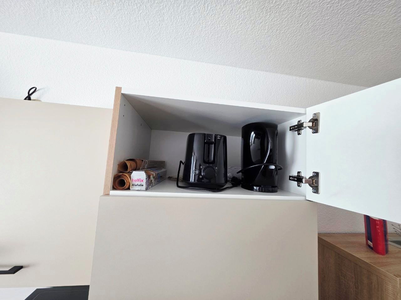 Ett köksutrymme med en inbyggd kaffemaskin och en förpackning med kaffekapslar.